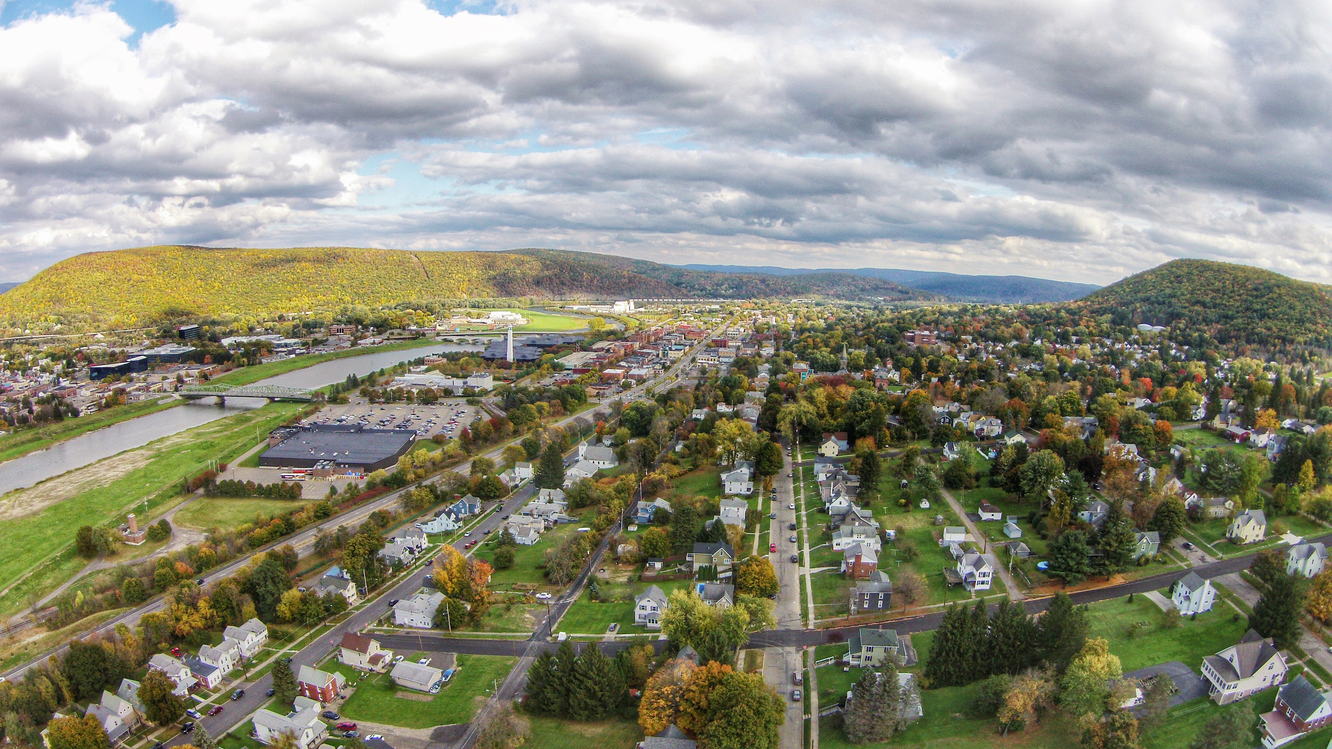 Aerial view of a small upstate New York town in autumn, surrounded by wooded hills